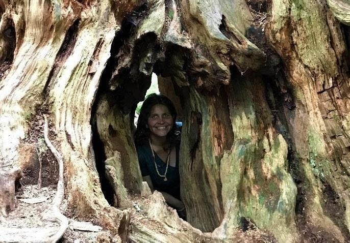 Charushila smiling thru tree trunk